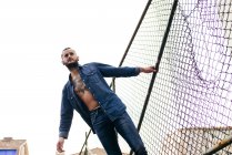Mann in Jeans posiert auf Metallzaun — Stockfoto
