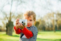 Kid at countryside taking a photo with a compact camera — Stock Photo