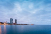 Serene landscape of coastline with skyscrapers against dusk sky — Stock Photo