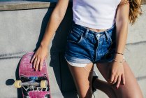 Cortar menina posando com skate velho — Fotografia de Stock
