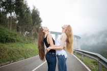 Dos chicas posando en un camino nublado . - foto de stock