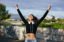 Happy girl with hands up on cityscape — Stock Photo