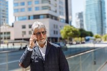 Зрелый мужчина разговаривает по телефону на улице — стоковое фото