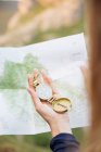 Imagem de corte da mão feminina segurando bússola dourada sobre o mapa — Fotografia de Stock