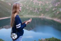 Girl using compass at mountain lake — Stock Photo
