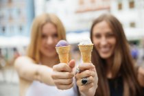 Портрет веселих дівчат, що показують конуси морозива на камеру — стокове фото