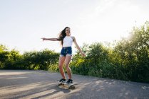 Chica montando skate alegremente - foto de stock