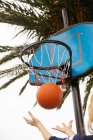 Низький кут зору баскетболу падає крізь кільце — стокове фото