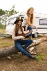Две девушки сидят на дереве и играют на укулеле — стоковое фото