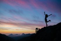 Silhouette of girl jumping on cliff — Stock Photo