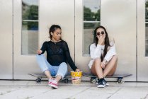 Stylish teens with popcorn on skates — Stock Photo