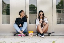 Stylish teens with popcorn on skates — Stock Photo