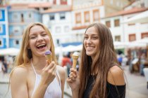 Портрет веселых девушек, которые едят мороженое на улице — стоковое фото