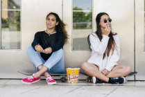 Adolescenti alla moda con popcorn sui pattini — Foto stock