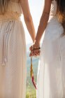 Обрежьте двух женщин, держащихся за руки — стоковое фото