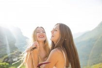 Happy girlfriends in sunlight against of mountains — Stock Photo