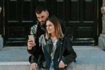 Объятие пары просмотра смартфона на улице — стоковое фото