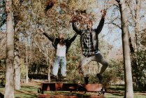 Happy couple in midair while throwing dry leaves up high — Stock Photo