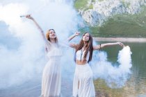 Дві дівчини з спалахами позує на озері — стокове фото