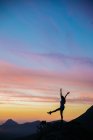 Силуэт туриста, аплодирующего закату с руками и ногами на фоне удивительного неба — стоковое фото