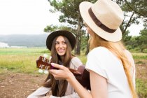 Девушка играет на укулеле перед брюнеткой — стоковое фото