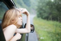 Mädchen setzt Gesicht aus Autofenster — Stockfoto