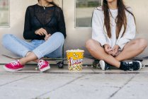 Adolescenti alla moda con popcorn sui pattini — Foto stock