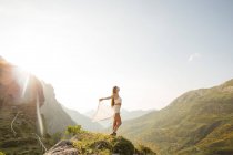 Вид сбоку молодой брюнетки, наслаждающейся свободой на фоне горного ландшафта при солнечном свете — стоковое фото