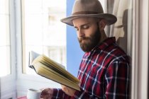 Мужчина с книгой пьет кофе — стоковое фото