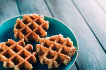 Waffles in dish over grunge wood — Stock Photo