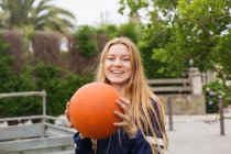 Portrait fille blonde tenant le basket et regardant la caméra sur la scène urbaine — Photo de stock