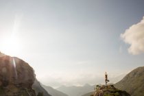 Silueta de mujer posando en la cima de la montaña contra el cielo increíble - foto de stock