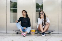 Les adolescents élégants avec du pop-corn sur les patins — Photo de stock