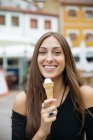 Portrait of brunette girl holding ice cream and looking at camera — Stock Photo