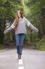 Portrait of girl in gray sweater walking on road and looking at camera — Stock Photo