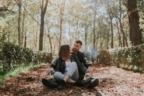 Portrait of couple sitting on pavement in park — Stock Photo