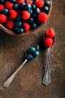 Blueberries and raspberries with vintage spoons — Stock Photo