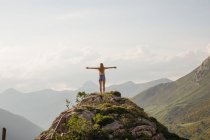 Vista trasera de la mujer posando contra el paisaje de montañas y nubes en el cielo - foto de stock