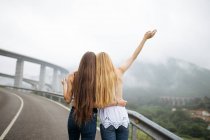 Two girls hugging on foggy mountain road — Stock Photo