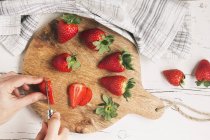 Manos de mujer cortando fresas - foto de stock
