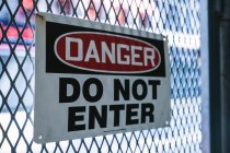 Знак опасности на заборе — стоковое фото