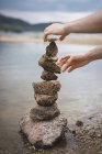 Coltivare le mani facendo torre di pietra sulla spiaggia — Foto stock