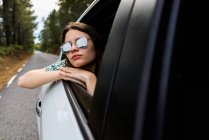 Stylish girl looking out of car window — Stock Photo