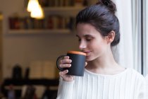 Brunette girl with eyes closed drinking cup of cocoa — Stock Photo