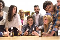 Colegas alegres conversando uns com os outros com garrafas de cerveja nas mãos emfesta de escritório — Fotografia de Stock