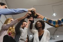 Vista a basso angolo delle persone che sbattono le bottiglie in ufficio durante il teambuilding — Foto stock