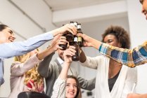 Portrait of people clanging bottles at office party — Stock Photo