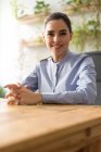 Smiling businesswoman sitting at workplace and looking at camera — Stock Photo