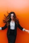 Счастливая предпринимательница позирует у оранжевой стены — стоковое фото