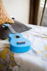 Голубая гитара, лежащая на кровати — стоковое фото